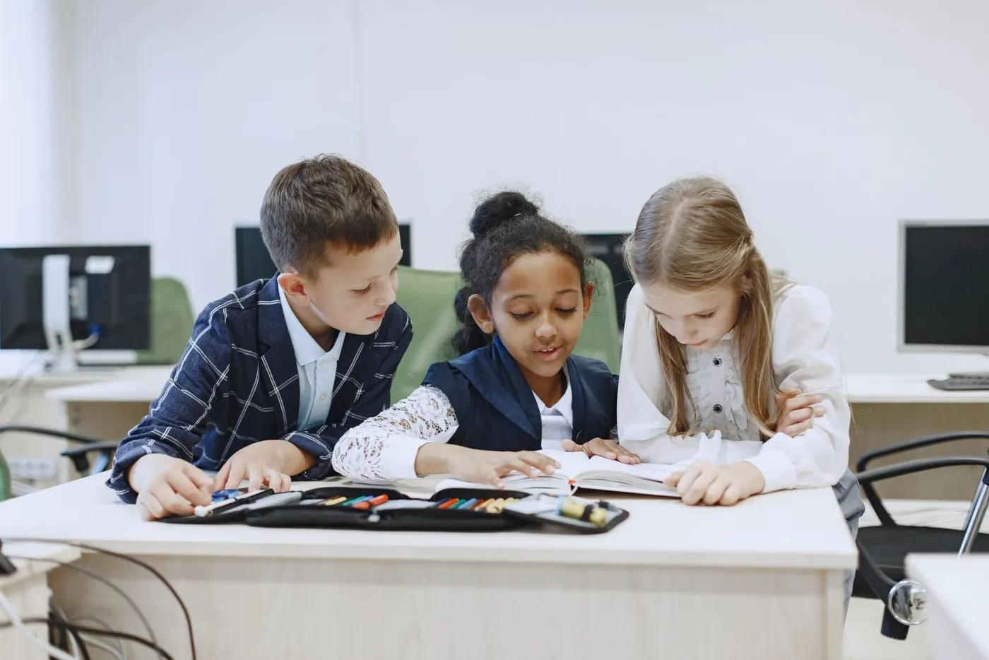 Three children of different backgrounds working together at a classroom desk